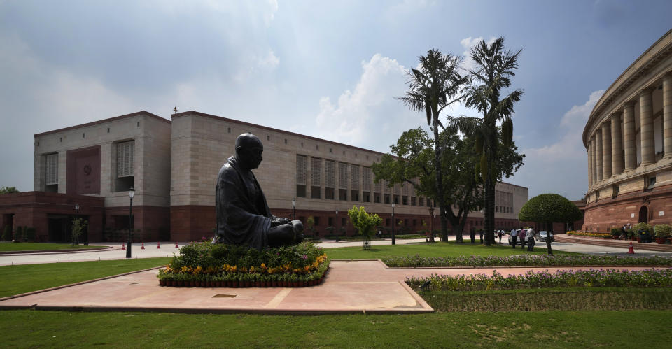 A statue of Mahatma Gandhi sits between the old and new Parliament House on the opening day of the monsoon session of the Indian parliament, in New Delhi, India, Thursday, July 20, 2023. Indian prime minister Narendra Modi Thursday broke more than two months of his public silence over the deadly ethnic clashes that have marred the country's remote northeast Manipur state, a day after a viral video showed two women being paraded naked by a mob, sparking outrage across the nation. (AP Photo/Manish Swarup)