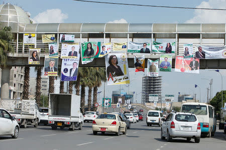 Vehicles drive under campaign posters ahead of the parliamentary election, in Erbil, Iraq April 15, 2018. REUTERS/Azad Lashkari