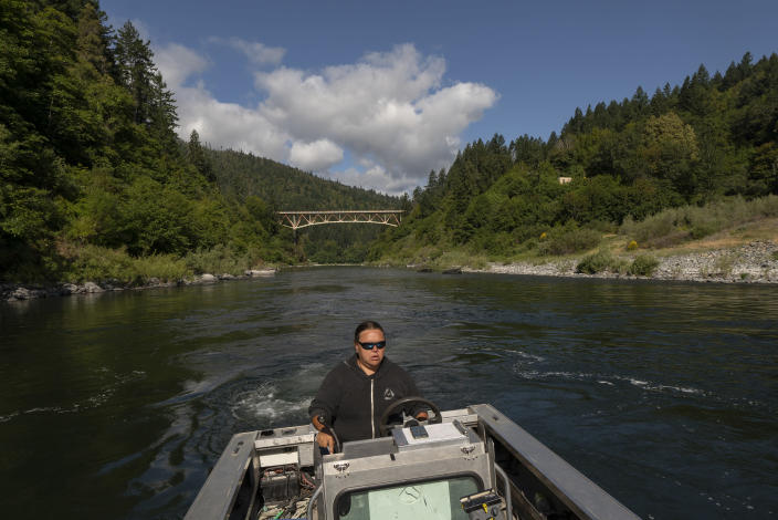 Jamie Holt, lead fisheries technician for the Yurok Tribe, maneuvers a boat near a fish trap in the lower Klamath River on Tuesday, June 8, 2021, in Weitchpec, Calif. A historic drought and low water levels are threatening the existence of fish species along the 257-mile long river. "When I first started this job 23 years ago, extinction was never a part of the conversation," she said of the salmon. "If we have another year like we're seeing now, extinction is what we're talking about." (AP Photo/Nathan Howard)
