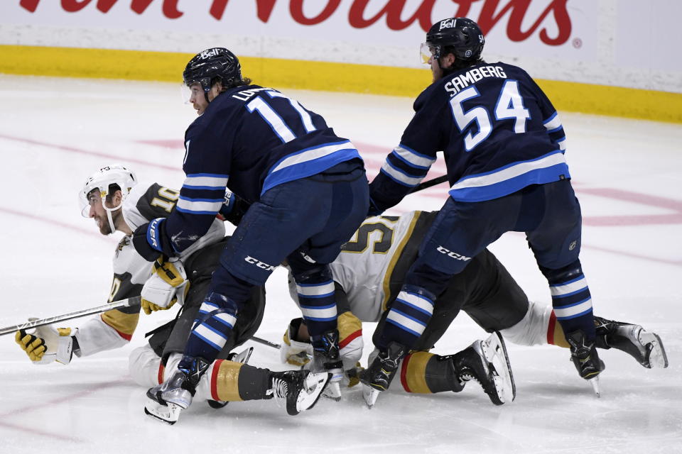 Winnipeg Jets' Adam Lowry (17) and Dylan Samberg (54) check Vegas Golden Knights' Nicolas Roy (10) and Keegan Kolesar (55) during the third period of an NHL hockey game in Winnipeg, Manitoba on Tuesday, Dec. 13, 2022. (Fred Greenslade/The Canadian Press via AP)