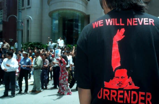 A supporter of Anwar Ibrahim wears a T-shirt bearing "We Will Never Surrender" while others chant "Reformasi" and "Allahu Akbar" during the launching of the People's Justice Party in Kuala Lumpur on Apr. 4, 1999. <span class="copyright">Reuters</span>