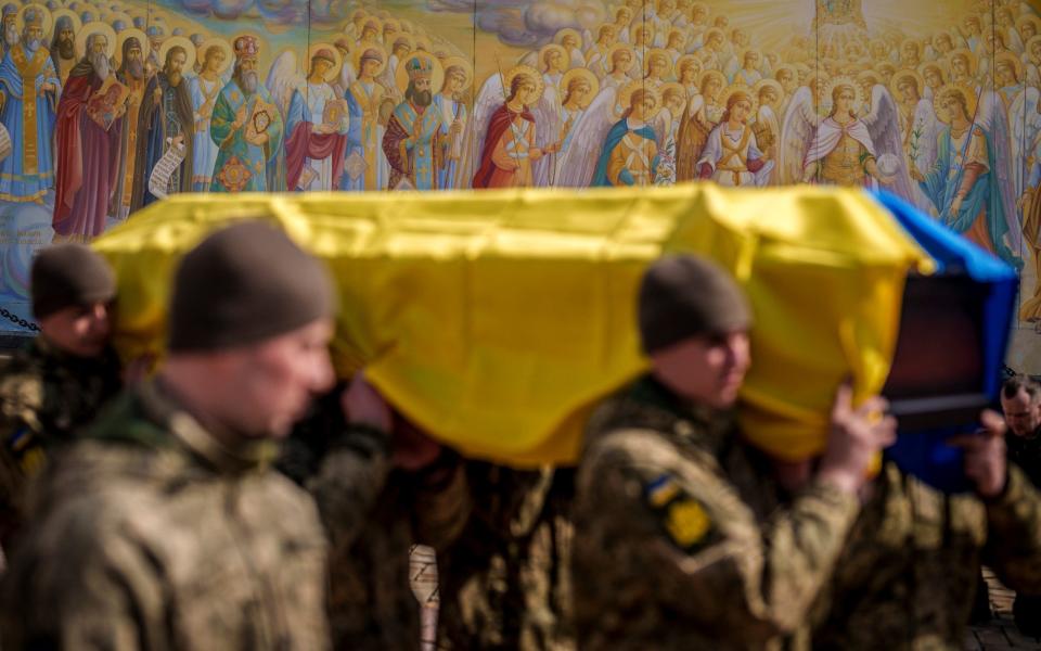 Ukrainian servicemen carry the coffin of a fallen soldier in front of St. Michael's Golden-Domed Monastery in Kyiv