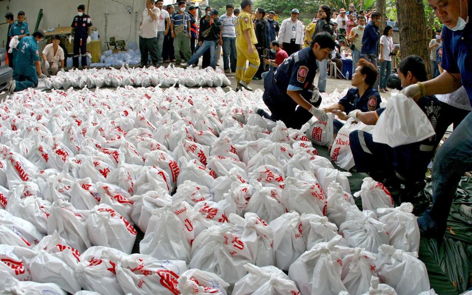 Members of a rescue foundation carry bags of corpses to the morgue store of a Buddhist temple in Bangkok on November 19, 2010