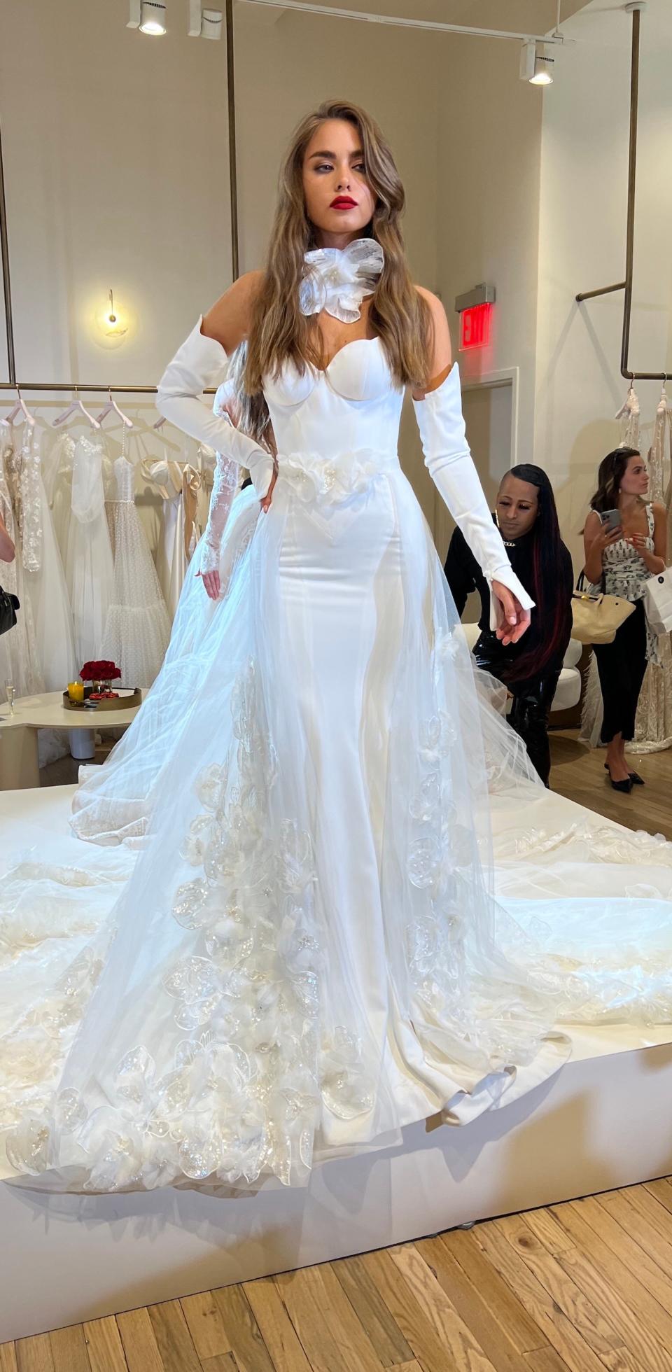 A woman poses in a wedding dress with a rosette around her neck.