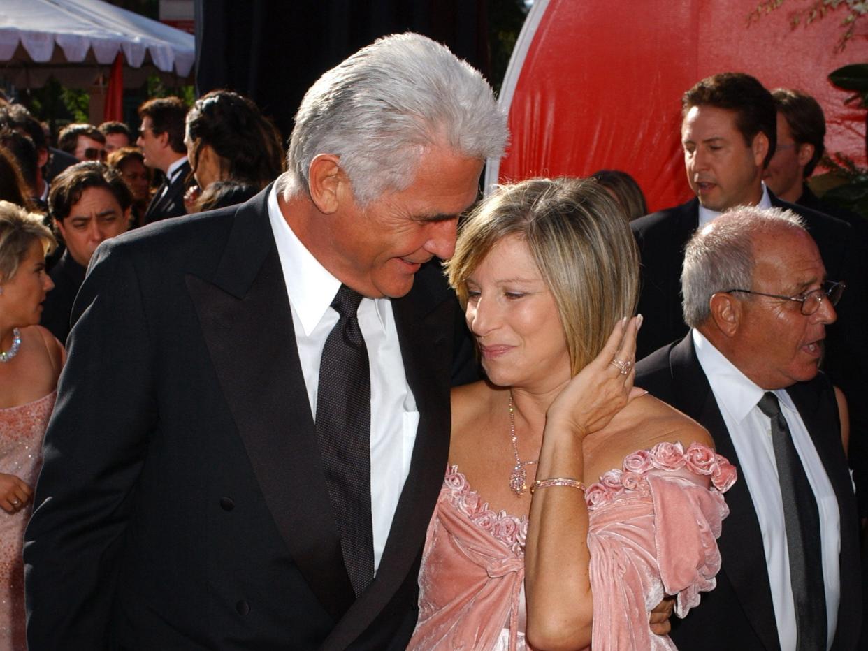 James Brolin, in a black suit, smiles at Barbra Streisand, in a pink velvet gown, on the red carpet at the 2004 Emmy Awards.