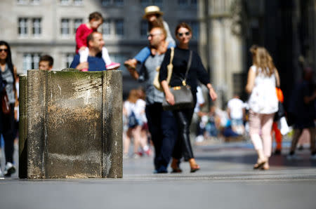 People walk past concrete barriers placed by police in front of the world famous gothic cathedral in Cologne, Germany, August 23, 2017. REUTERS/Wolfgang Rattay