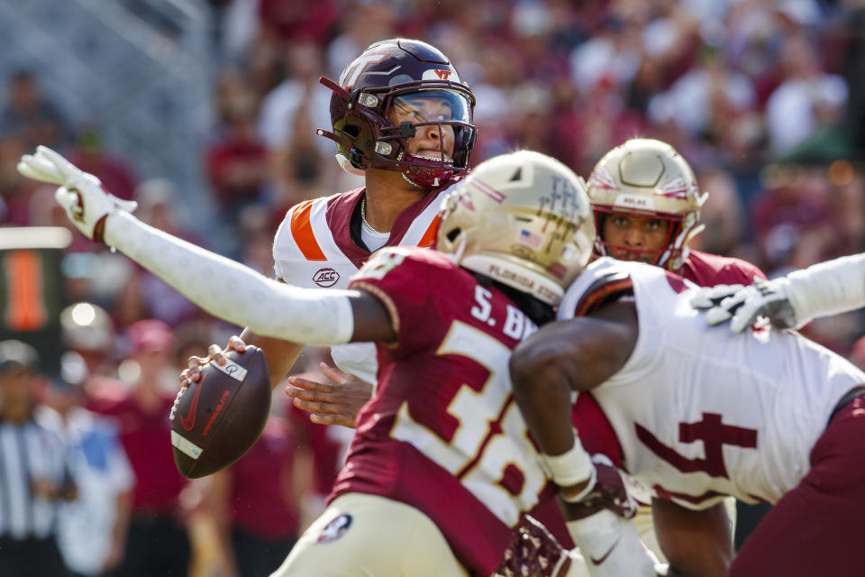 Virginia Tech quarterback Kyron Drones (1) looks for a receiver as Florida State defenders close in during the first half of an NCAA college football game, Saturday, Oct. 7, 2023, in Tallahassee, Fla. (AP Photo/Colin Hackley)