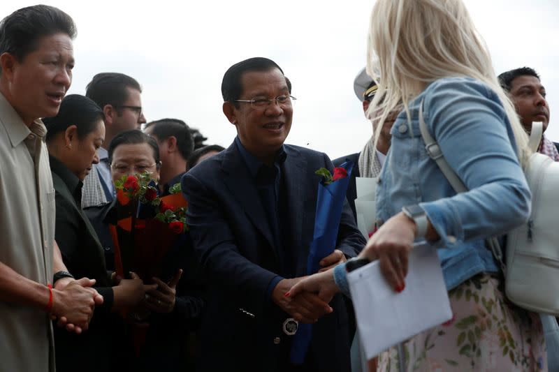Cambodia's Prime Minister Hun Sen welcomes a passenger of MS Westerdam, a cruise ship that spent two weeks at sea after being turned away by five countries over fears that someone aboard might have the coronavirus , as it docks in Sihanoukvil