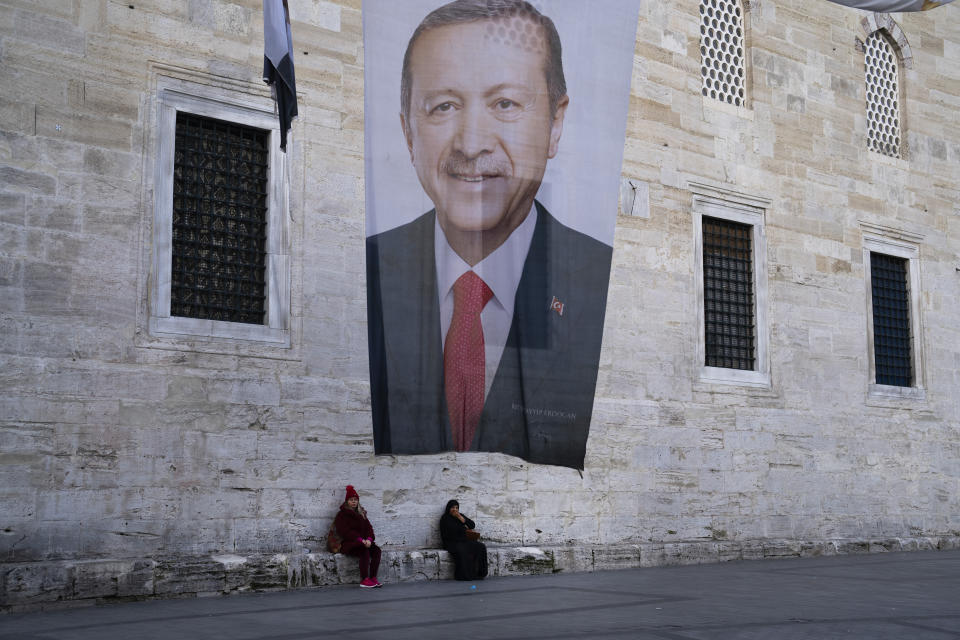 Two women sit near a campaign banner of Turkish President and leader of the Justice and Development Party, or AKP, Recep Tayyip in Istanbul, Turkey, Monday, March 11, 2024. Turkey was coming to terms on Monday with the opposition's unexpected success in local elections which saw it outperform President Recep Tayyip Erdogan's ruling party and add to municipalities gained five years ago. (AP Photo/Francisco Seco)