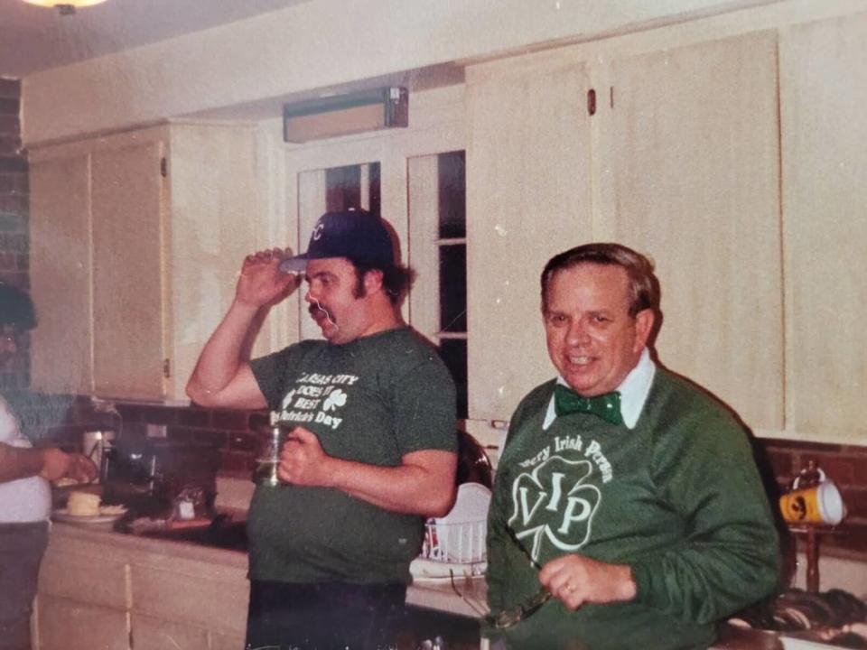 Mike Carroll, who died at 81, stands in a sweatshirt that says “very Irish person.” His granddaughter called him a “living, breathing leprechaun.”