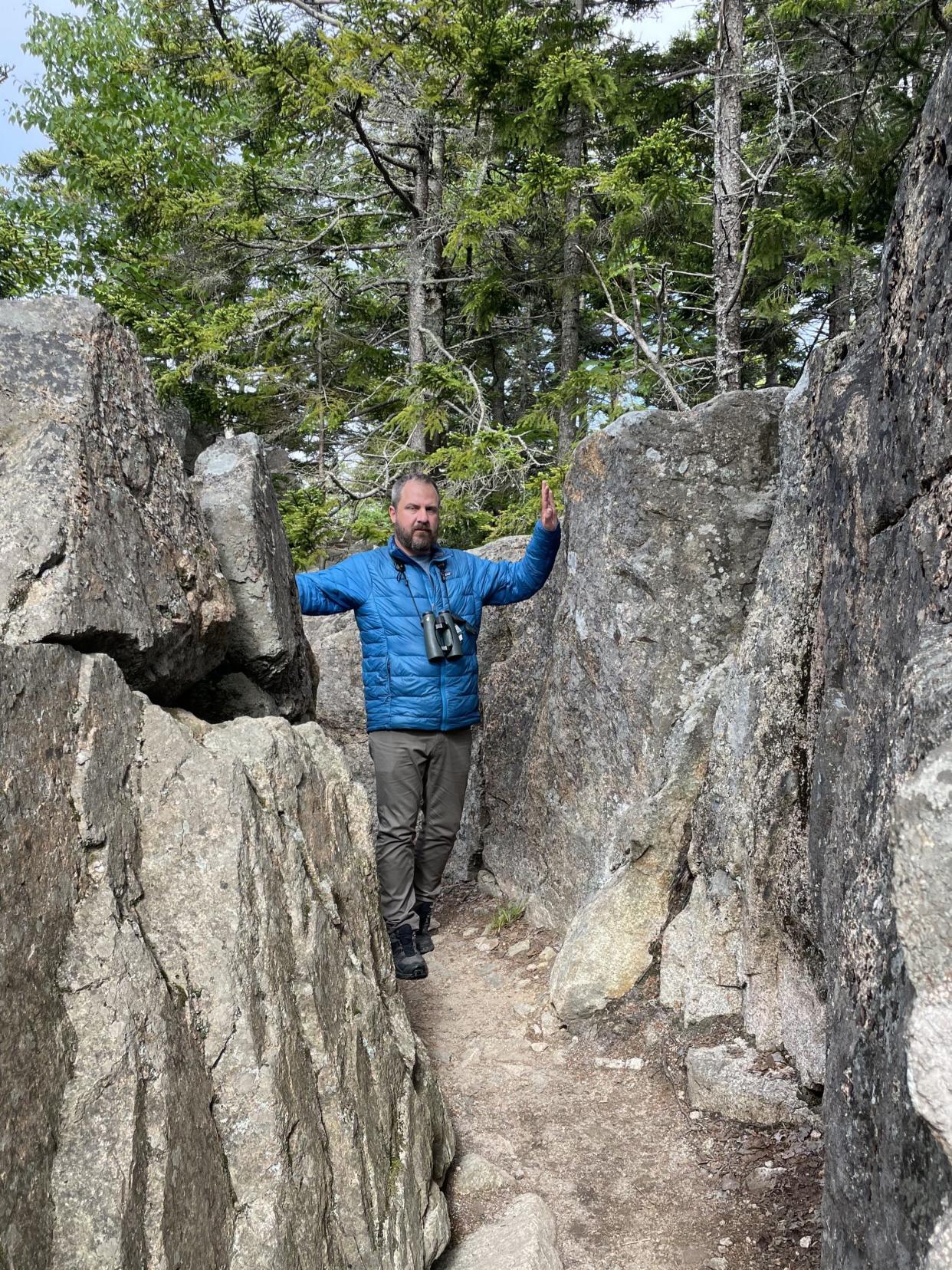 Goshen College grad Drew Weber, who works as project manager for the Merlin Bird ID App, looks for birds at Acadia National Park in Maine.