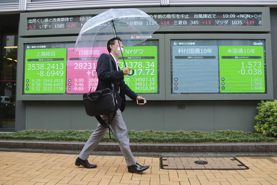 A man walks by an electronic stock board of a securities firm in Tokyo, Wednesday, Oct. 13, 2021. Shares were mixed in Asia on Wednesday after an up-and-down day on Wall Street ended with most benchmarks lower as traders waited for updates on inflation and corporate earnings. (AP Photo/Koji Sasahara)