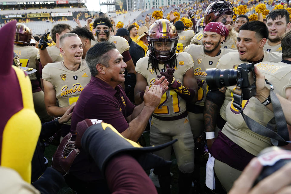 Arizona State interim head coach Shaun Aguano, front left, celebrates with players, including RJ Regan (21), after an NCAA college football game against Washington in Tempe, Ariz., Saturday, Oct. 8, 2022. (AP Photo/Ross D. Franklin)