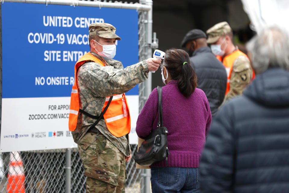 CORRECTS MONTH TO MARCH NOT FEBRUARY - A National Guard member checks the temperature of people entering the United Center mass COVID-19 vaccination site on Wednesday, March 10, 2021, in Chicago. The site will administer 6,000 shots per day at full capacity and will remain open seven days a week for eight weeks. (AP Photo/Shafkat Anowar)