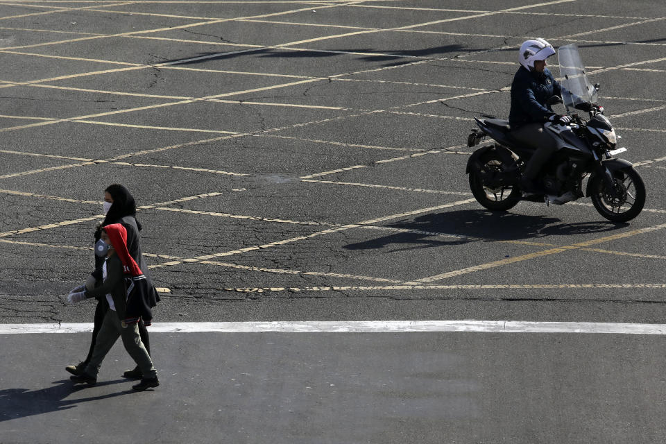 Pedestrians wearing face masks and gloves cross an intersection in northern Tehran, Iran, Wednesday, March 4, 2020. With deaths spiking in Iran and Italy and infections spreading quickly through Europe, the Mideast and the Americas, countries were considering new drastic measures to curb the new coronavirus that first emerged in China. (AP Photo/Vahid Salemi)