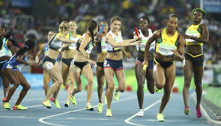 2016 Rio Olympics - Athletics - Preliminary - Women's 4 x 400m Relay Round 1 - Olympic Stadium - Rio de Janeiro, Brazil - 19/08/2016. Competitors pass their batons for the third leg of the race. REUTERS/Lucy Nicholson