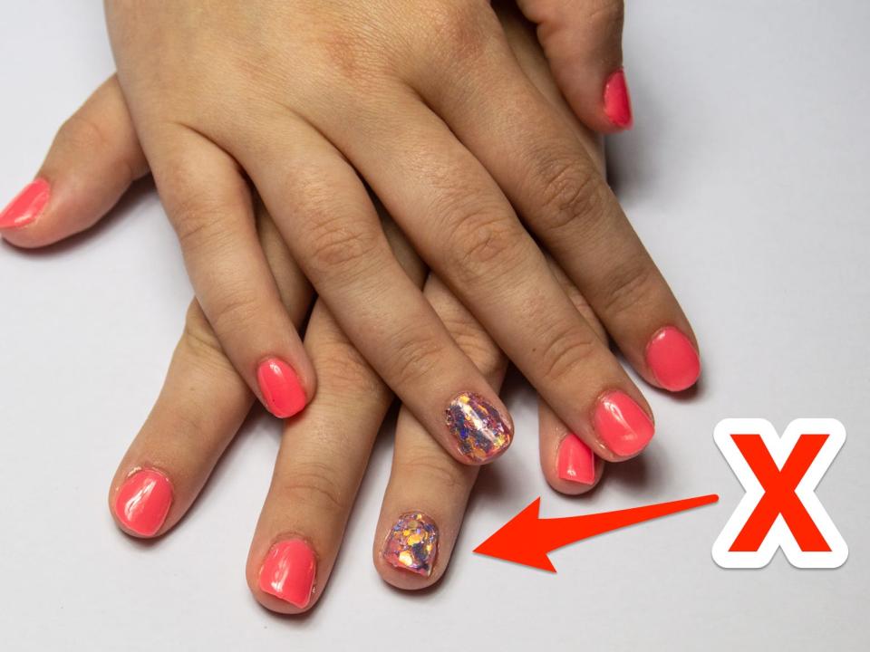 An 'X' pointing at an accent nail with glitter.