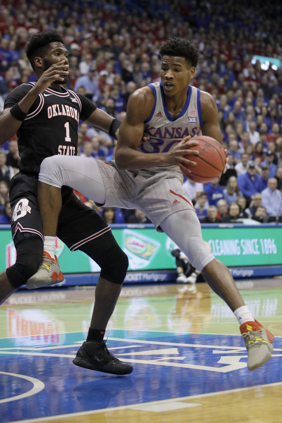 Kansas guard Ochai Agbaji (30) drives against Oklahoma State guard Jonathan Laurent (1) during the first half of an NCAA college basketball game in Lawrence, Kan., Monday, Feb. 24, 2020. (AP Photo/Orlin Wagner)