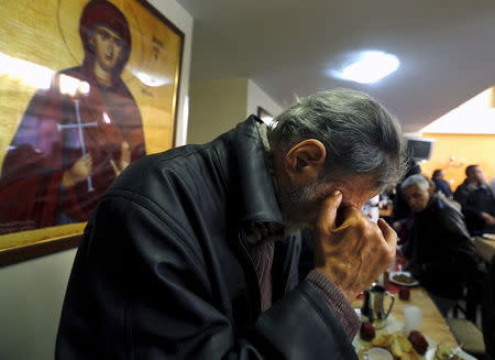 A man prays before his lunch at the Orthodox church "Galini" foundation soup kitchen in Athens, Greece in this March 19, 2015 file photo. REUTERS/Yannis Behrakis/Files