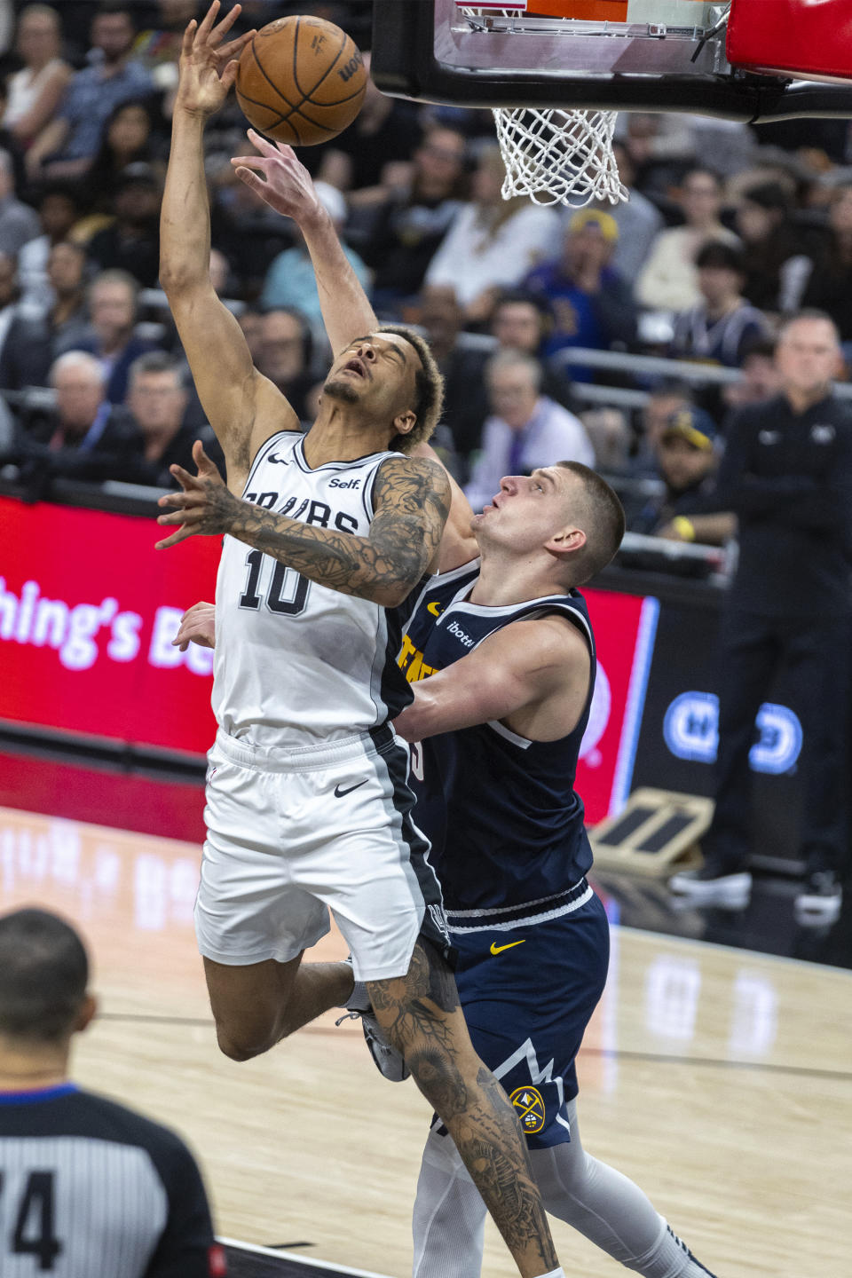 San Antonio Spurs forward Jeremy Sochan (10) is defended by Denver Nuggets center Nikola Jokic, right, during the second half of an NBA basketball game, Friday, March 15, 2024, in Austin, Texas. (AP Photo/Stephen Spillman)