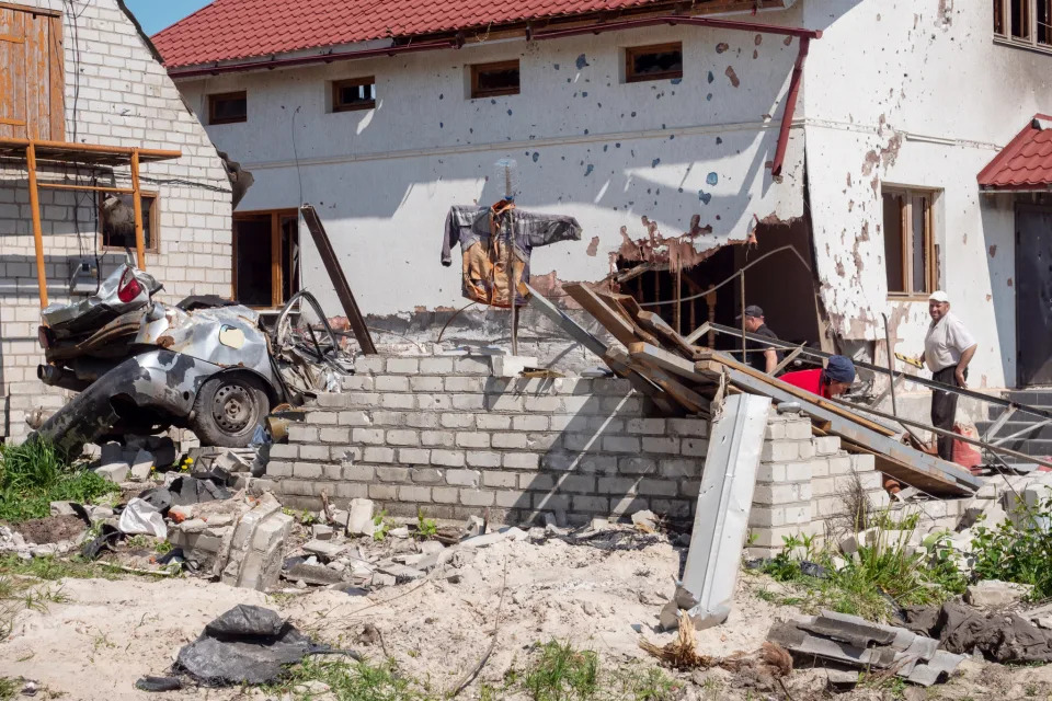 Sergey Ous, at right, stands outside his heavily damaged home in the village of Malaya Rohan, near Kharkiv. (Mo Abbas / NBC News)