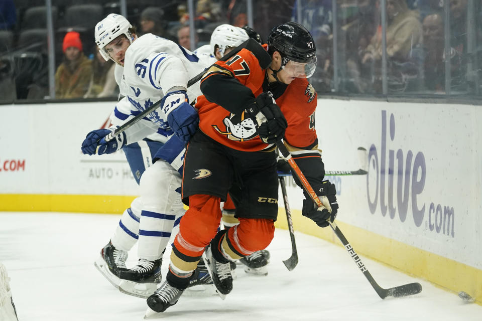 Anaheim Ducks' Hampus Lindholm, right, moves the puck past Toronto Maple Leafs' John Tavares during the first period of an NHL hockey game Sunday, Nov. 28, 2021, in Anaheim, Calif. (AP Photo/Jae C. Hong)
