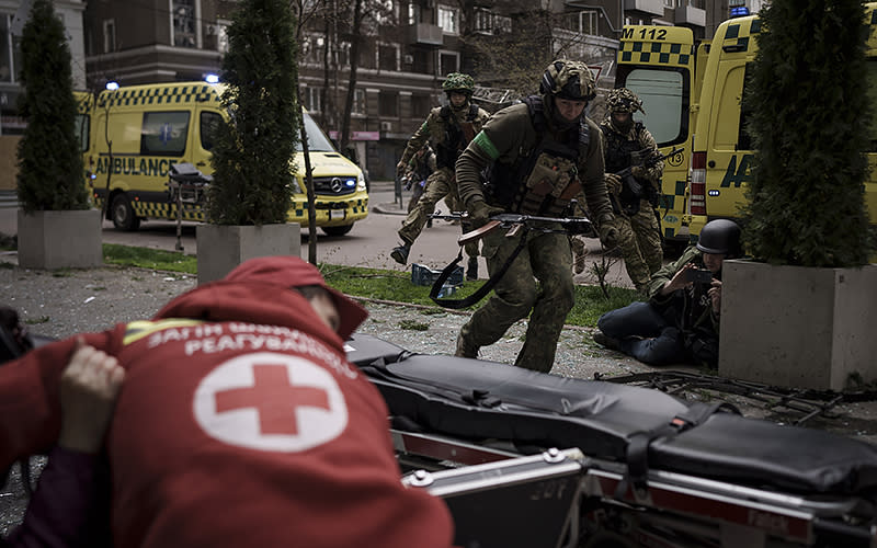 Ukrainian service members run for cover as explosions are heard during a Russian attack in downtown Kharkiv, Ukraine, on April 17. <em>Associated Press/Felipe Dana</em>