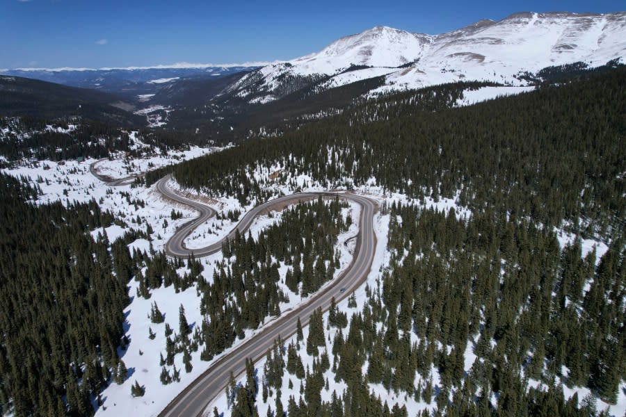 A road winds through the snow-covered Rocky Mountains at Hoosier Pass as seen from the air, Monday, April 18, 2022, near Blue River, Colo. Some drought-prone communities in the U.S. West are mapping snow by air to refine their water forecasts. It’s one way water managers are adjusting as climate change disrupts weather patterns and makes current forecasting methods less reliable. (AP Photo/Brittany Peterson)