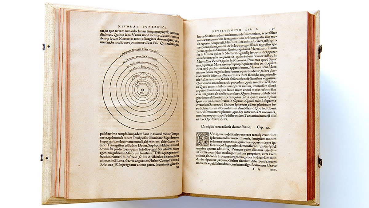  An open book showing a diagram of planet orbits on the left and text in latin on the right. 