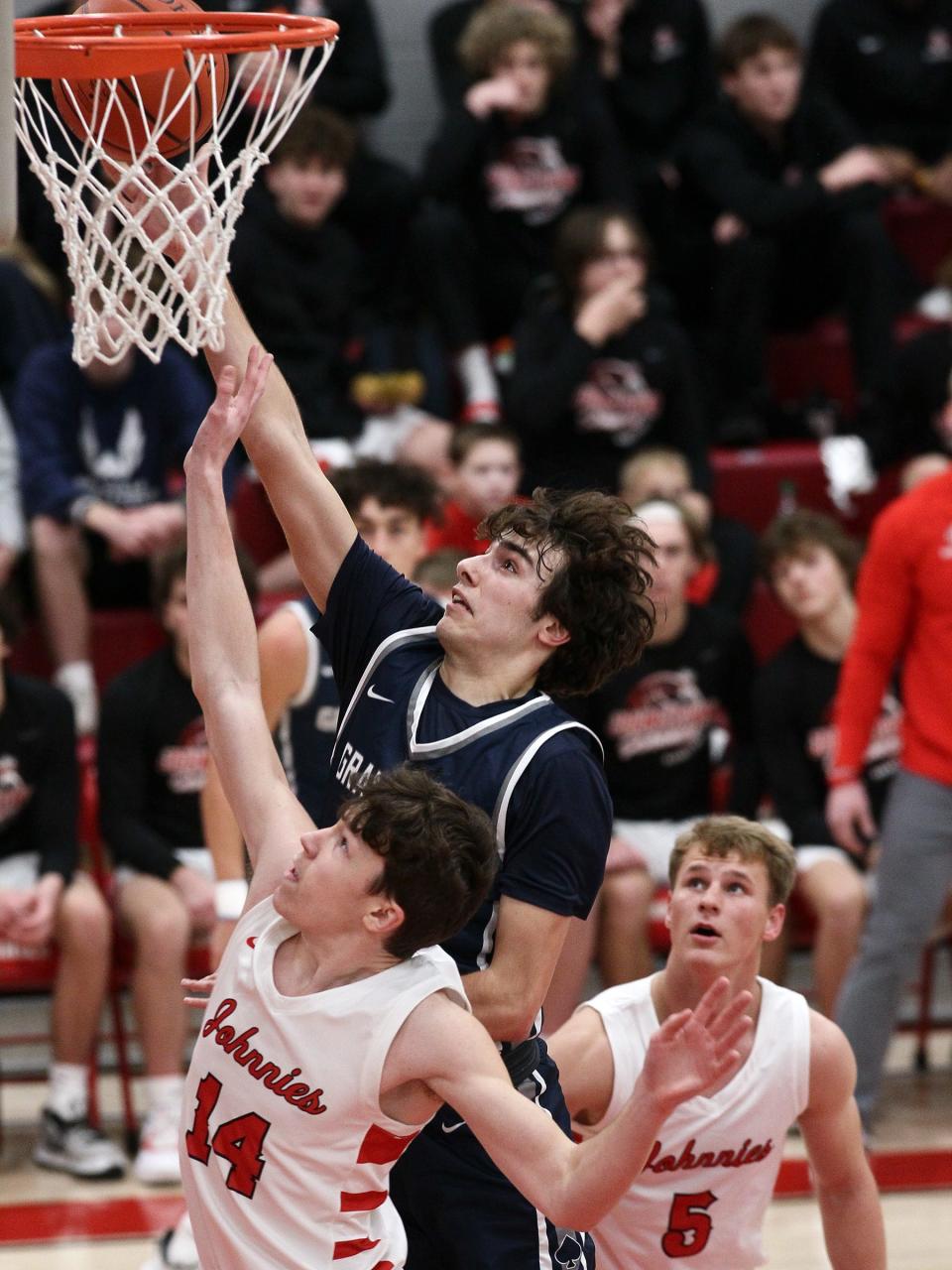 Granville junior Alex Engle reaches for the basket while under pressure from Johnstown junior Kyle Siegfried (14) and senior Caleb Schneider (5) Wednesday night during the Johnnies' 49-31 victory. 