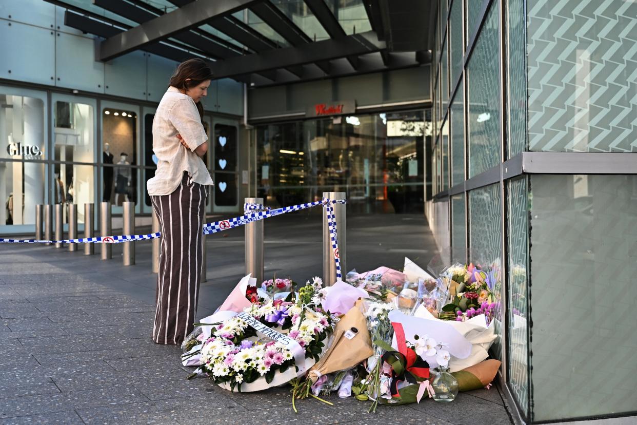 A person looks at floral tributes for victims of the attack left at the entrance to Westfield Bondi Junction shopping centre in Sydney (via REUTERS)