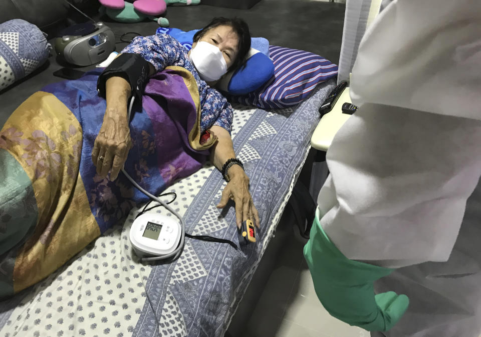 A woman feared to have COVID is monitored by a volunteer from the "Saimai Will Survive" group Friday, July 23, 2021, in Bangkok, Thailand. As Thailand's medical system struggles beneath a surge of coronavirus cases, ordinary people are helping to plug the gaps, risking their own health to bring care and supplies to often terrified, exhausted patients who've fallen through the cracks. (AP Photo/Tassanee Vejpongsa)