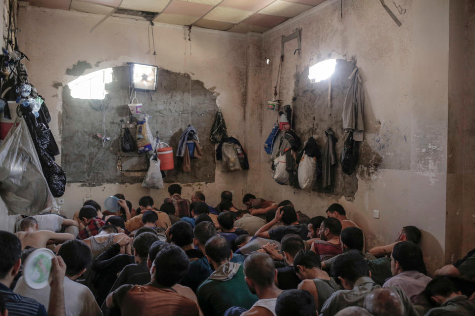 FILE - In this Tuesday, July 18, 2017 file photo, Suspected Islamic State members sit inside a small room in a prison south of Mosul, Iraq. A leading international human rights organization is criticizing the Iraqi government for holding thousands of prisoners, including children, in degrading and "inhuman" conditions. (AP Photo/Bram Janssen, File)