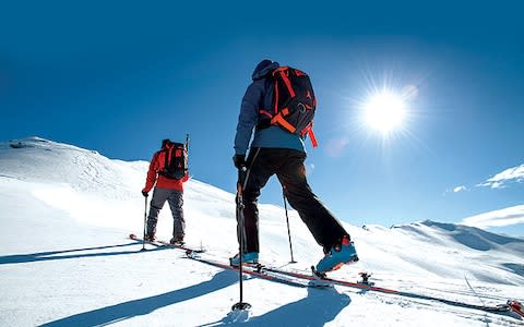 Two ski tourers skin uphill using hike and ride boots - Credit: ATOMIC
