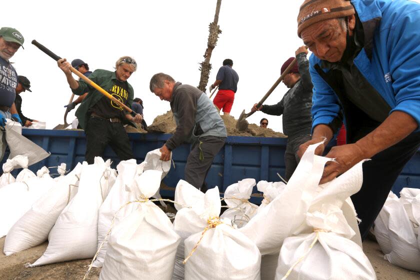 LONG BEACH, CA - FEBRUARY 3, 2024 - - Residents, with the help of lifeguards, collect bags of sand in preparations for upcoming storm at the 72nd Place Lifeguard Station in Long Beach on February 3, 2024. Officials across Southern California are warning residents to prepare for what could be "life threatening and damaging flooding," beginning Sunday. (Genaro Molina/Los Angeles Times)