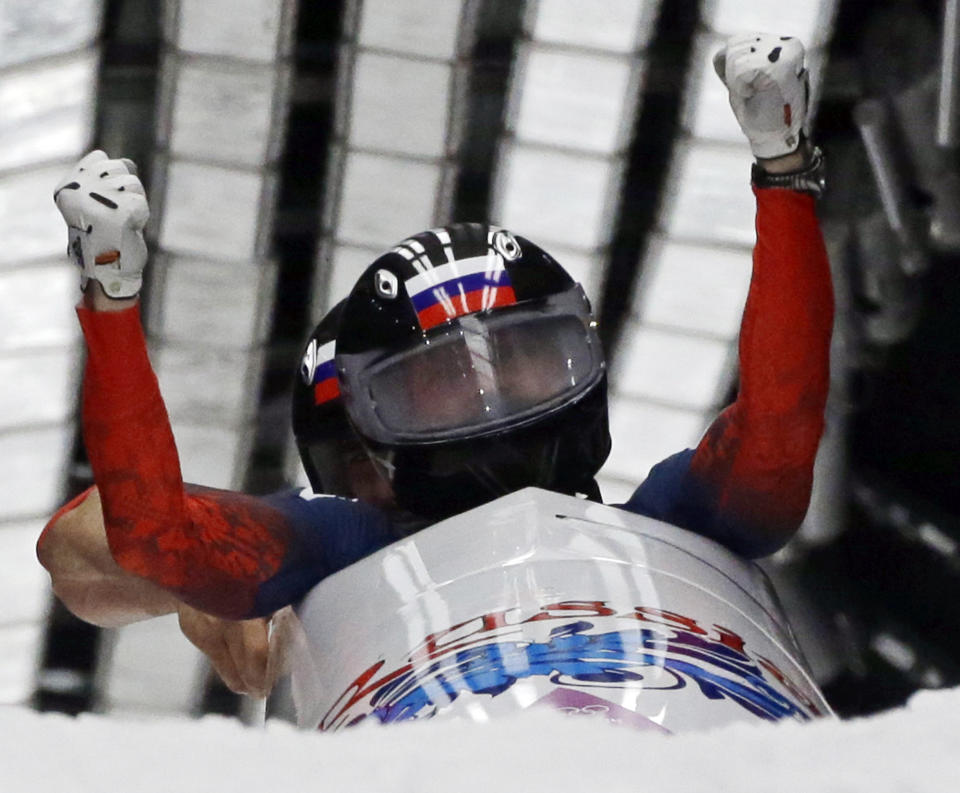 The team from Russia RUS-1, piloted by Alexander Zubkov and brakeman Alexey Voevoda, cross into the finish area to win the gold medal during the men's two-man bobsled competition at the 2014 Winter Olympics, Monday, Feb. 17, 2014, in Krasnaya Polyana, Russia. (AP Photo/Dita Alangkara)