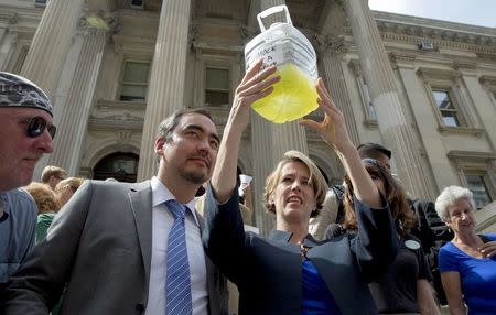 New York State democratic governor candidate Zephyr Teachout (R) holds a a bottle of frack contaminated water as lieutenant governor running mate Tim Wu (2nd L) looks on during a campaign event in New York September 3, 2014. REUTERS/Brendan McDermid/File Photo