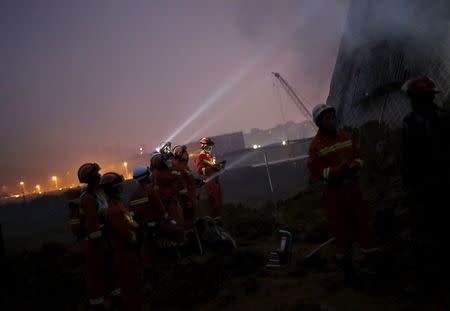 Firefighters use flashlights to search for survivors among the debris of collapsed buildings after a landslide hit an industrial park in Shenzhen, Guangzhou, China, December 20, 2015. REUTERS/Tyrone Siu