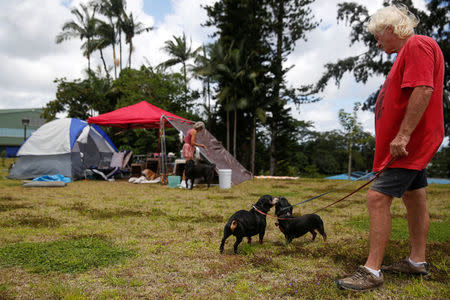 Eddie McLaren, of Kapoho, walks two of his five dogs near his tents at a Red Cross evacuation center in Pahoa during ongoing eruptions of the Kilauea Volcano in Hawaii, U.S., May 15, 2018. REUTERS/Terray Sylvester