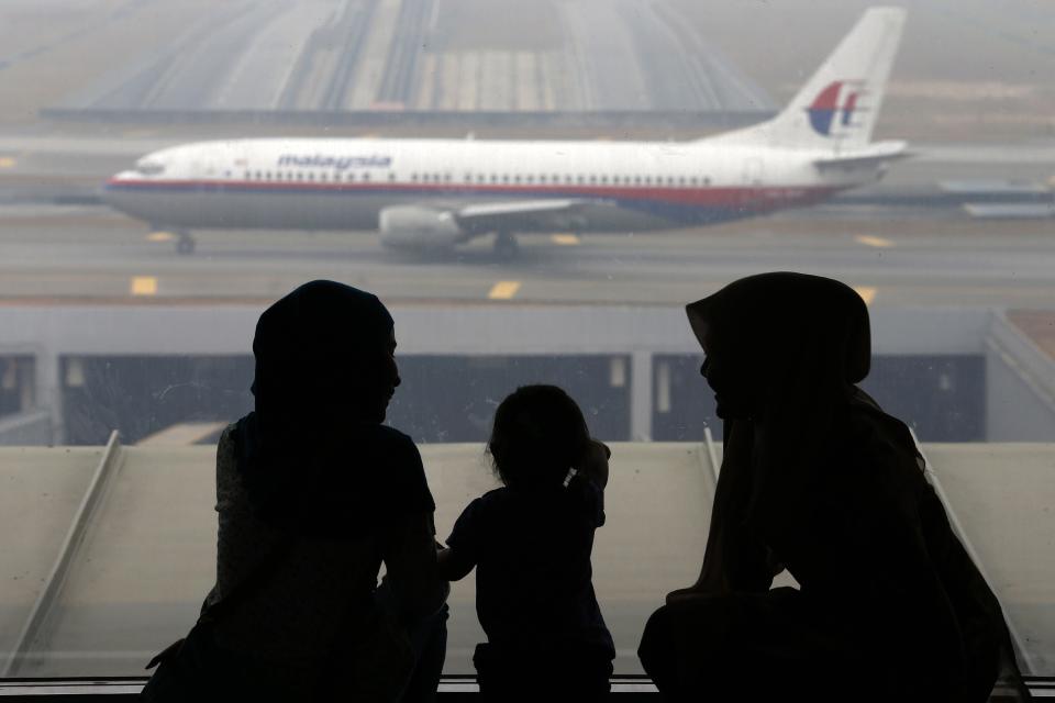 Women and a girl look at a Malaysia Airlines plane on the tarmac of Kuala Lumpur International Airport