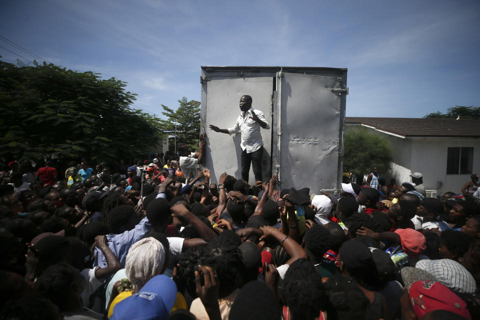 A man tries to calm hungry people worried they won't receive a handout, after a government distribution of food and school supplies was temporarily suspended when the lines turned into jostling crowds, at the mayor's office in Cite Soleil, Port-au-Prince, Haiti, Thursday, Oct. 3, 2019. The administration of President Jovenel Moise tried to alleviate Haiti’s economic crunch on Thursday by distributing plates of rice and beans, sacks of rice, and school backpacks filled with four notebooks and two pens. (AP Photo/Rebecca Blackwell)