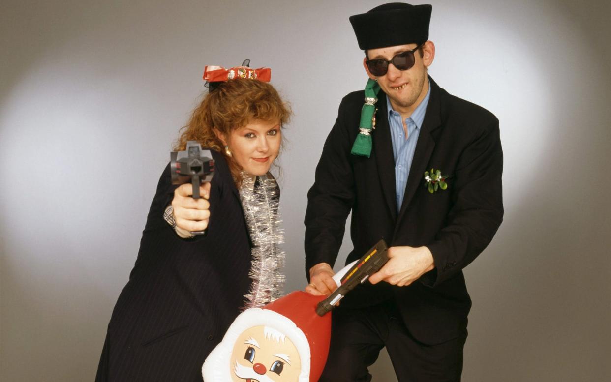 Singers Kirsty MacColl (1959 - 2000) and Shane MacGowan with toy guns and an inflatable Santa in a festive scenario, circa 1987 - Tim Roney/HULTON 