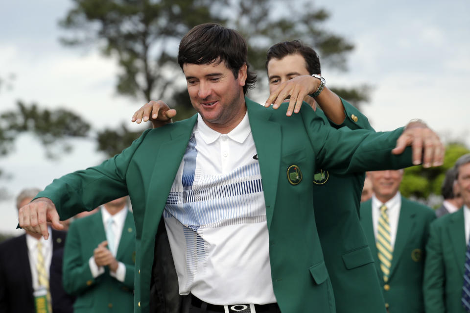 Defending Masters' champion Adam Scott, of Australia, helps Bubba Watson, left, with his green jacket after winning the Masters golf tournament Sunday, April 13, 2014, in Augusta, Ga. (AP Photo/David J. Phillip)