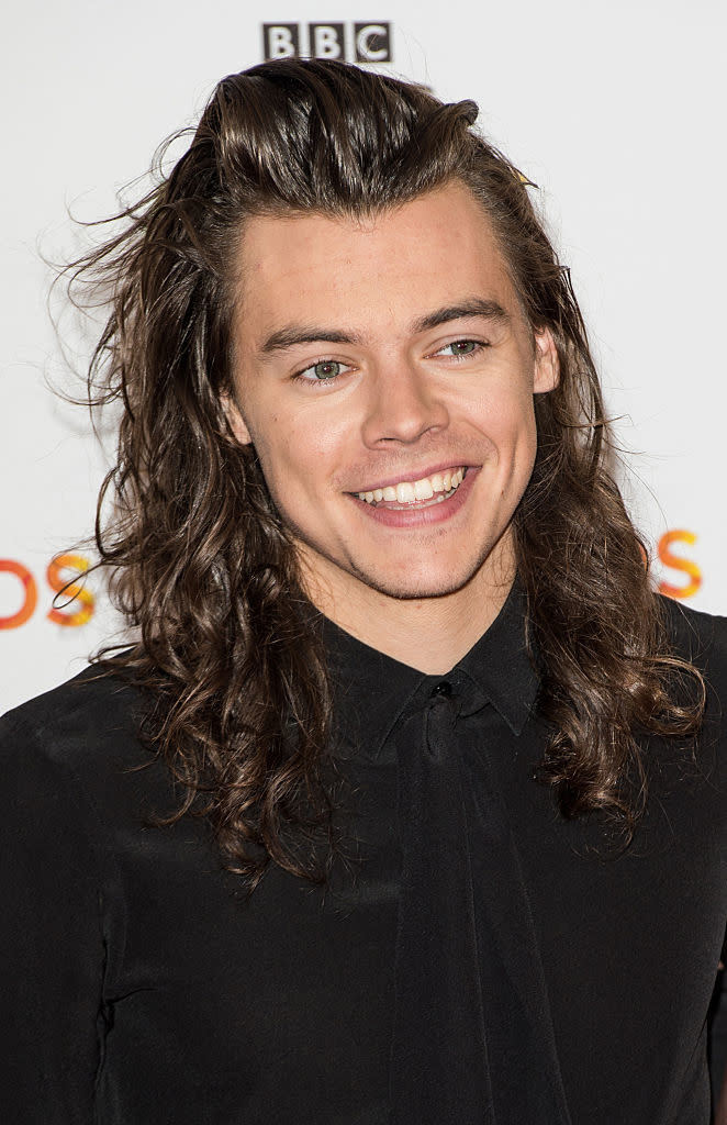 Harry smiling on a red carpet with long hair