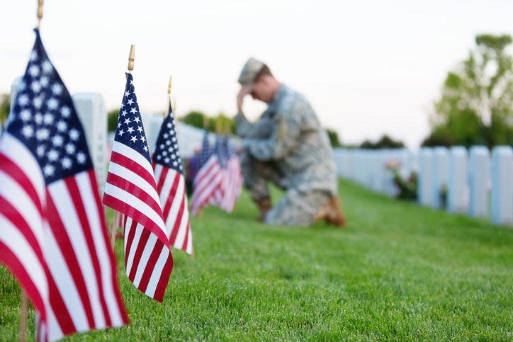 American soldier kneeling at a veterans grave on Memorial Day.
