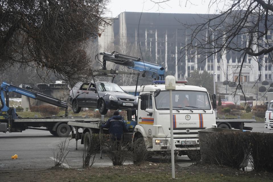 A tow truck transports a car, which was damaged during clashes, from the central square with the city hall in the background in Almaty, Kazakhstan, Tuesday, Jan. 11, 2022. Life in Almaty, which was affected with the violence the most during protests, started returning to normal this week, with public transport resuming operation and malls reopening. (Vladimir Tretyakov/NUR.KZ via AP)