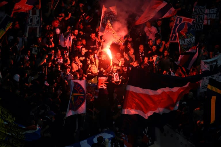 Paris Saint-Germain's supporters hold flags and burn a flare on April 1, 2017, at the Parc Olympique Lyonnais stadium in Decines-Charpieu, near Lyon