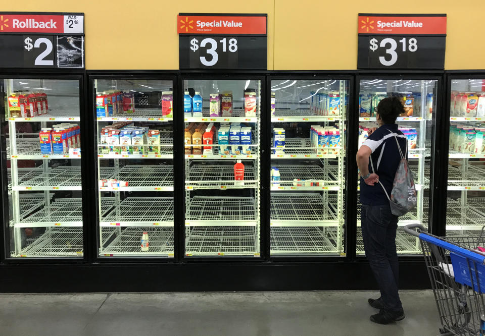 A unidentified woman looks over bare refrigerator shelves in a Walmart in Houston.