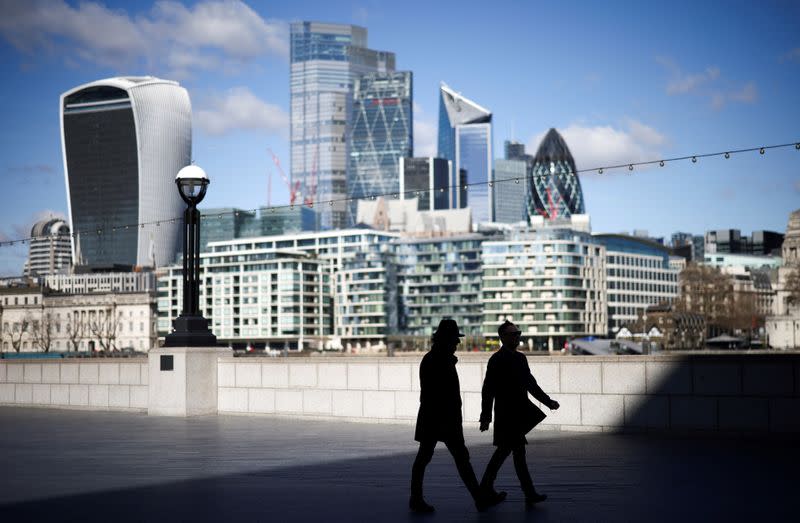 FILE PHOTO: The City of London financial district can be seen as people walk along the south side of the River Thames, amid the coronavirus disease (COVID-19) outbreak in London