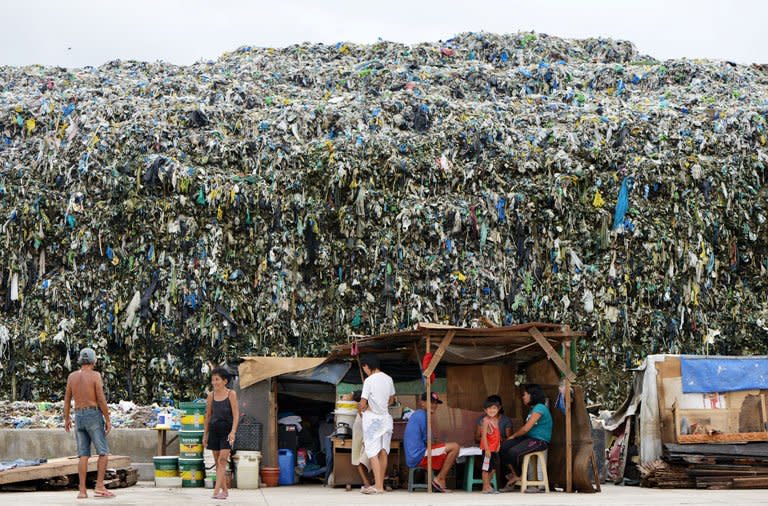 People outside their homes near a rubbish dump in Manila on Wednesday. The Philippines financial capital banned disposable plastic shopping bags and styrofoam food containers Thursday, as part of escalating efforts across the nation's capital to curb rubbish blamed for deadly flooding